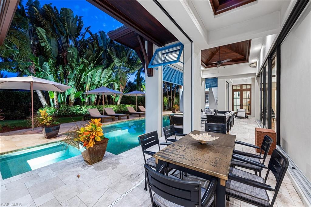 2284 Crayton Road Naples, FL 34103 - Photo 16 of 34 a view of a patio with table and chairs potted plants with wooden floor and fence