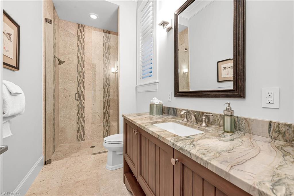 2284 Crayton Road Naples, FL 34103 - Photo 29 of 34 a bathroom with a granite countertop sink a toilet a shower and a mirror