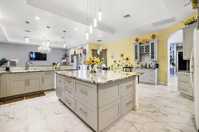 a kitchen with kitchen island granite countertop a sink counter top space appliances and cabinets