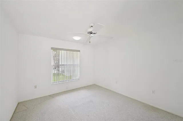an empty room with a window and ceiling fan