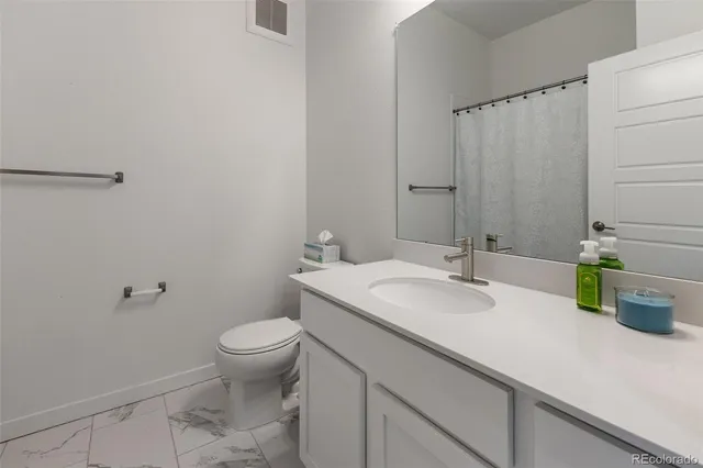a bathroom with a granite countertop sink a toilet and a mirror