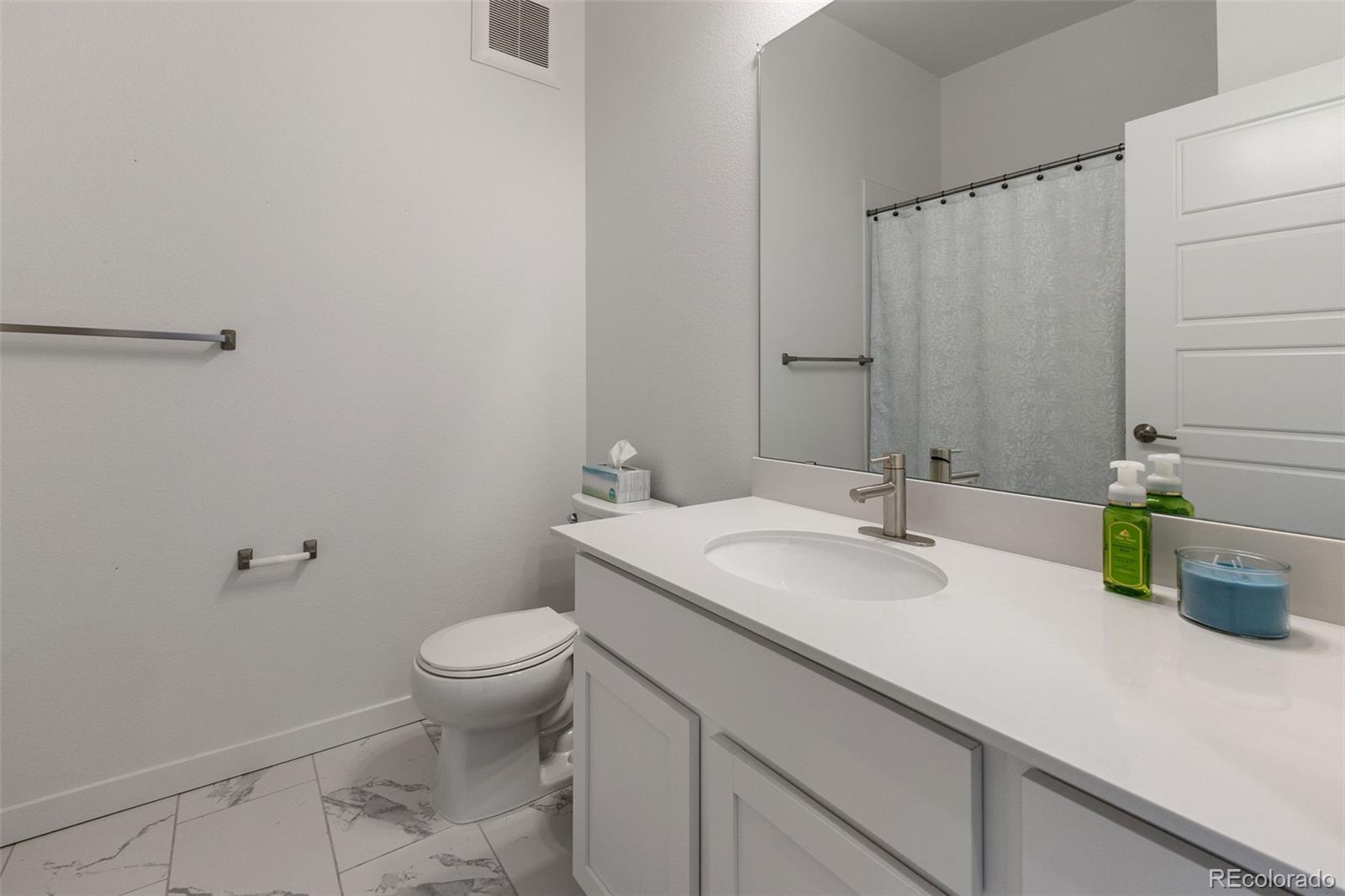 9287 Twenty Mile Road, Unit 401 Parker, CO 80134 - Photo 14 of 44 a bathroom with a granite countertop sink a toilet and a mirror