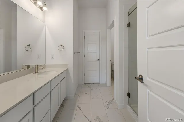 a bathroom with a granite countertop sink a mirror and a shower