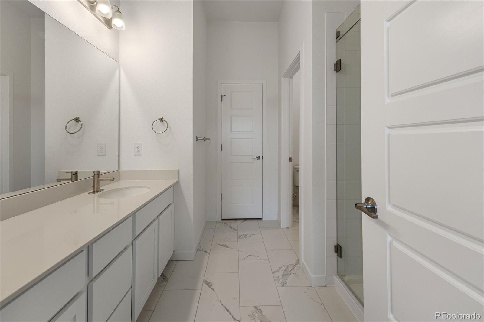 9287 Twenty Mile Road, Unit 401 Parker, CO 80134 - Photo 20 of 44 a bathroom with a granite countertop sink a mirror and a shower
