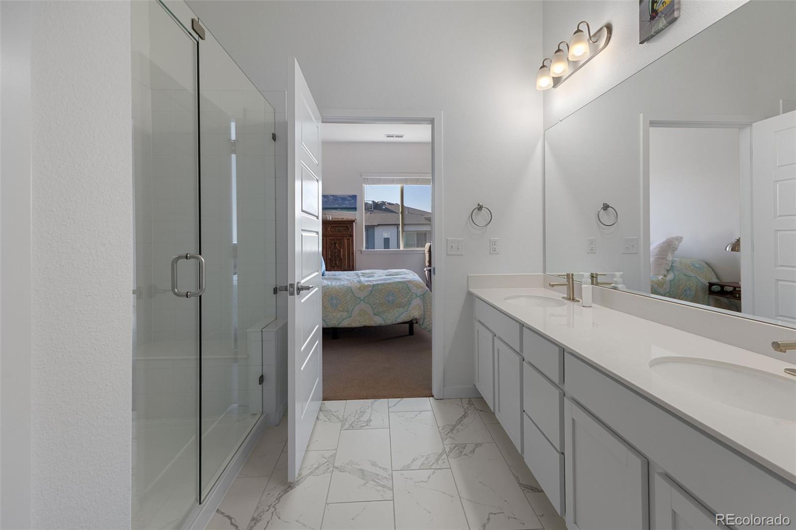 9287 Twenty Mile Road, Unit 401 Parker, CO 80134 - Photo 21 of 44 a en suite bathroom with a double vanity sink and a mirror