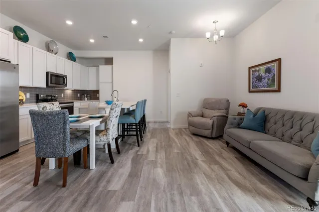 a living room with furniture a wooden floor and a view of kitchen