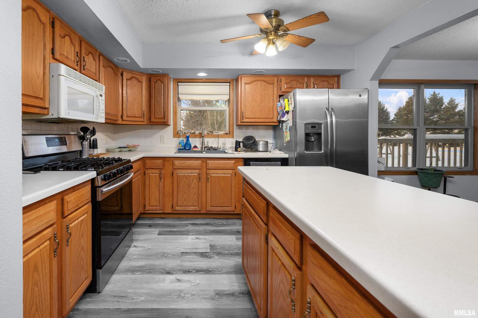 1231 90th Street Joy, IL 61260 - Photo 21 of 38 a kitchen with stainless steel appliances a sink dishwasher a stove top oven a refrigerator with island and cabinets