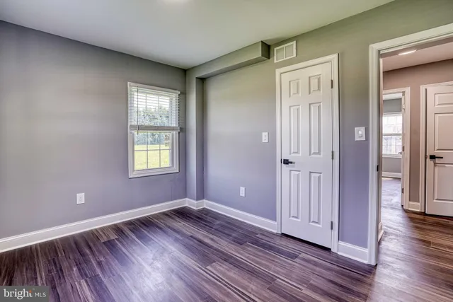 an empty room with wooden floor closet and windows