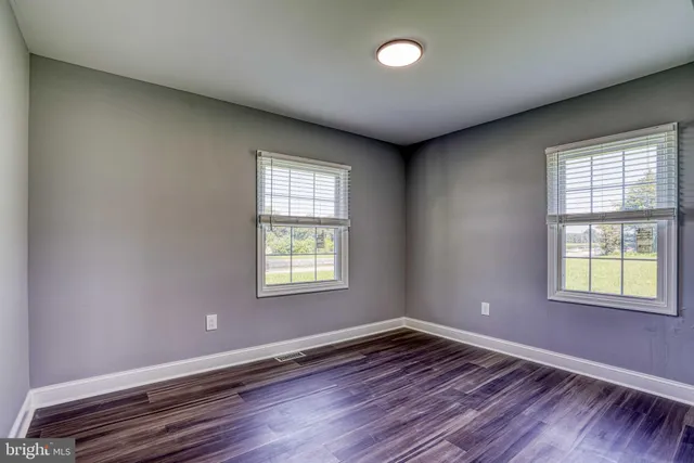 a view of an empty room with wooden floor and closet