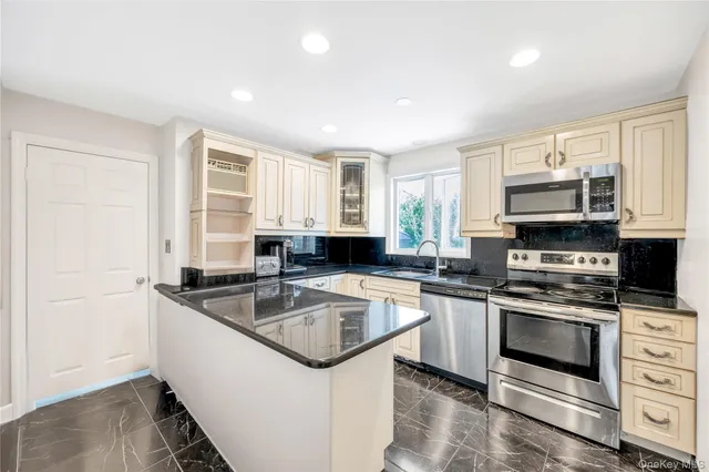a kitchen with granite countertop a sink stainless steel appliances and cabinets