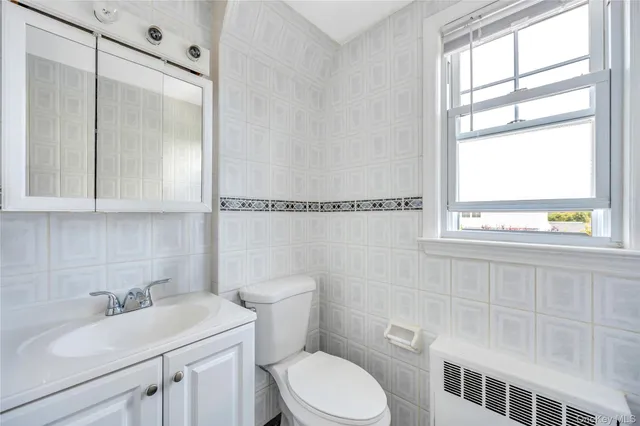 a bathroom with a sink toilet vanity and window