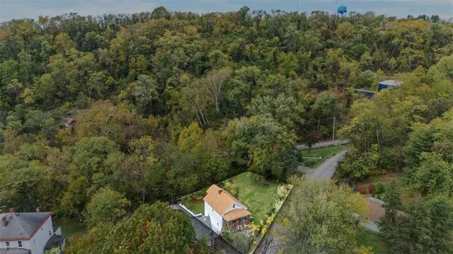 an aerial view of residential house with outdoor space and trees all around