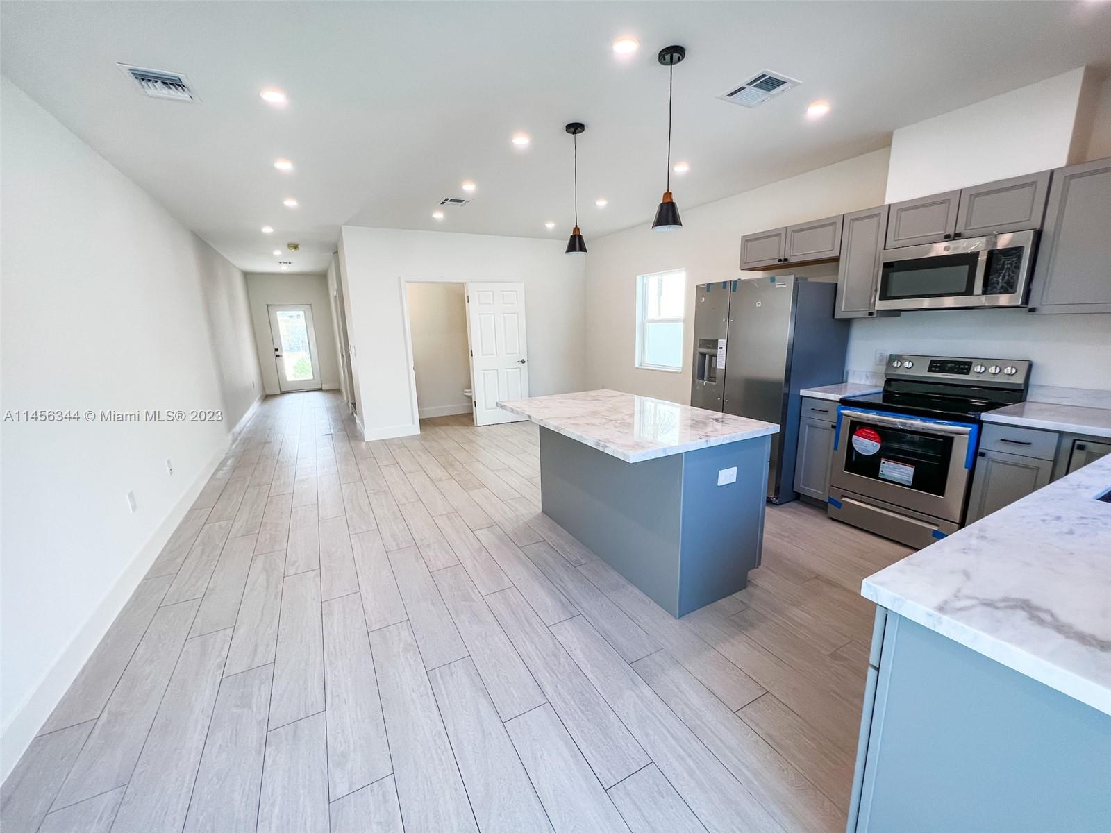 Collier City Pompano Beach, FL 33069 - Photo 23 of 28 a large kitchen with stainless steel appliances granite countertop a large counter top a stove and a wooden floors
