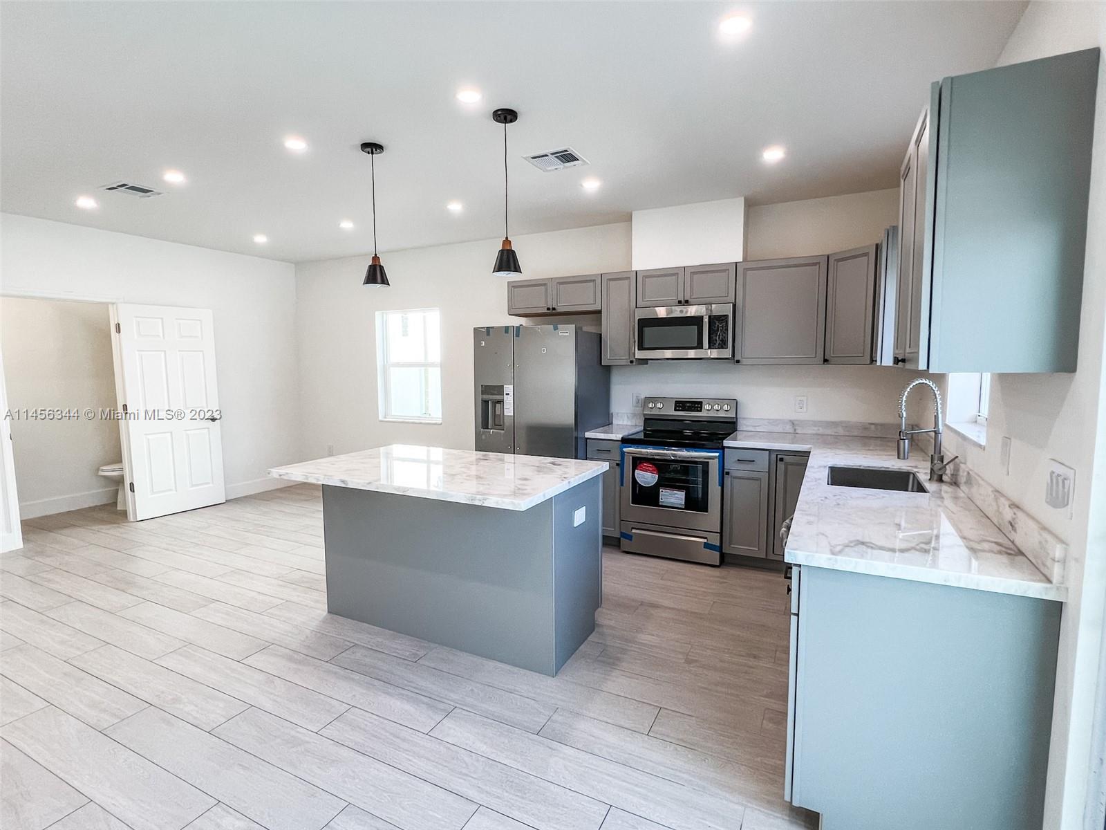 Collier City Pompano Beach, FL 33069 - Photo 5 of 28 a large kitchen with stainless steel appliances kitchen island granite countertop a large counter top and a stove top oven