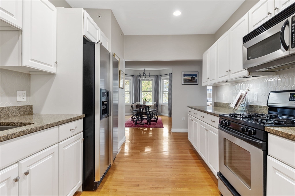 51 Dimick Street, Unit 5 Somerville, MA 02143 - Photo 15 of 28 a kitchen with stainless steel appliances granite countertop a stove top oven a sink dishwasher and cabinets with wooden floor