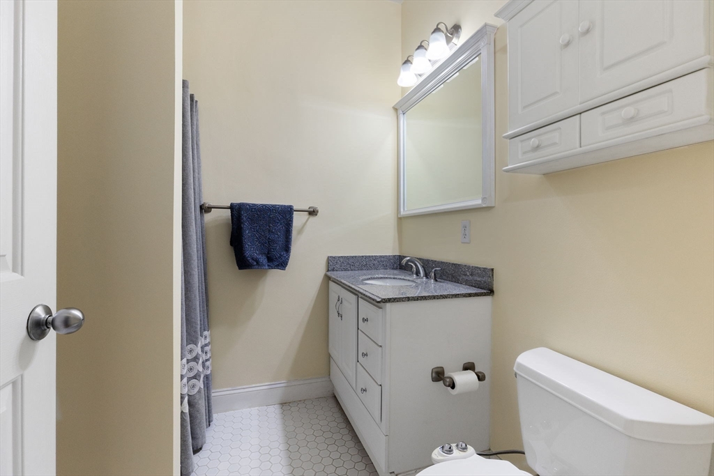 51 Dimick Street, Unit 5 Somerville, MA 02143 - Photo 22 of 28 a bathroom with a granite countertop sink a toilet and mirror