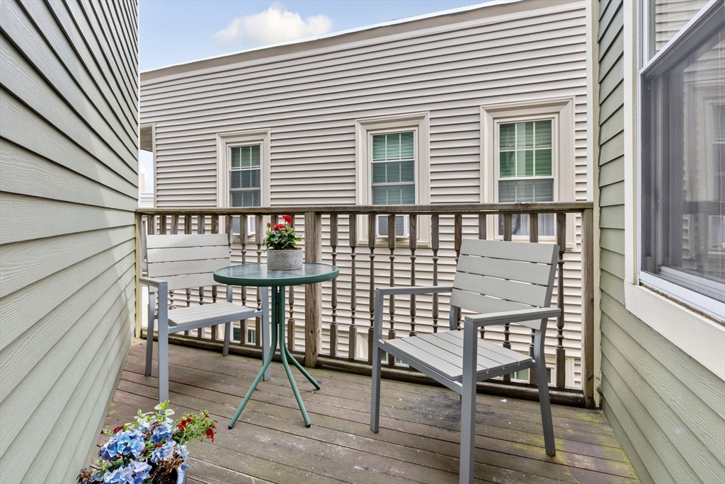 51 Dimick Street, Unit 5 Somerville, MA 02143 - Photo 26 of 28 a balcony with table and chairs and wooden floor