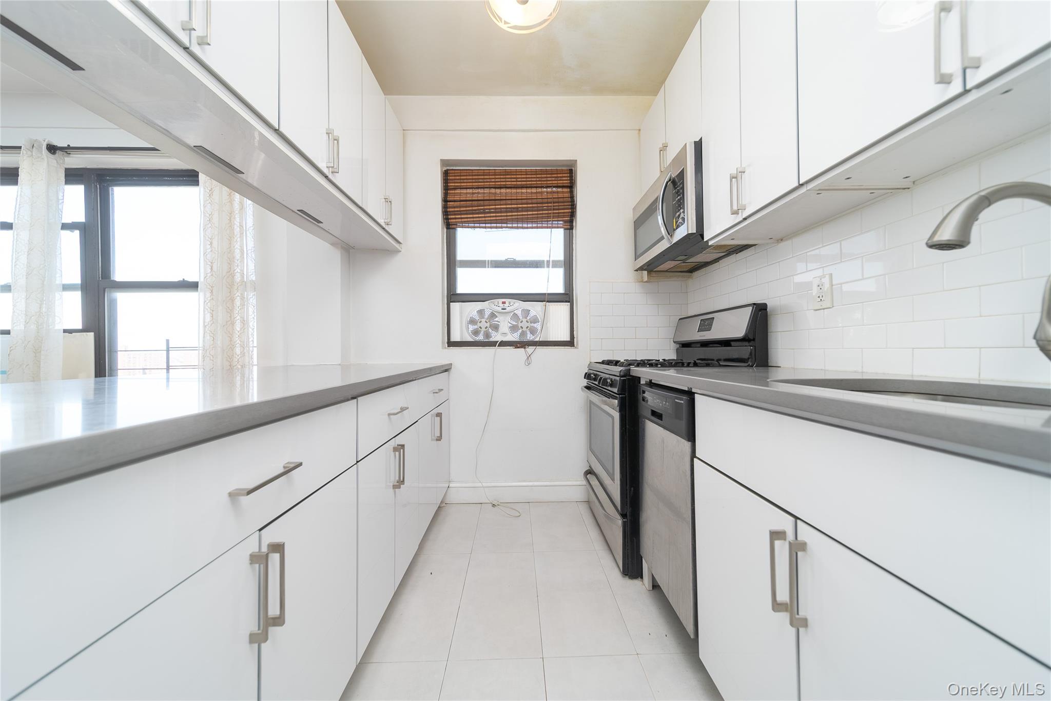 99-32 66th Road, Unit 9N Queens, NY 11374 - Photo 10 of 16 a kitchen with granite countertop white cabinets and white appliances
