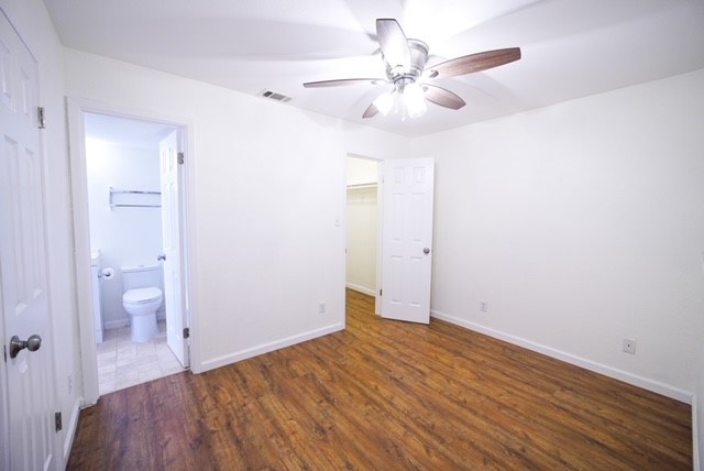 2500 Burleson Road, Unit 713 Austin, TX 78741 - Photo 9 of 15 A well-lit bedroom features rich wood flooring, a ceiling fan, and convenient access to a private bathroom and closet.
