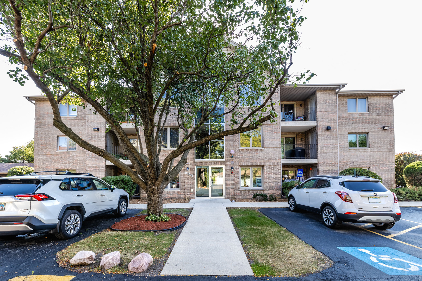 10288 SW Highway, Unit 3D Chicago Ridge, IL 60415 - Photo 3 of 4 a white house that has a tree in front of it