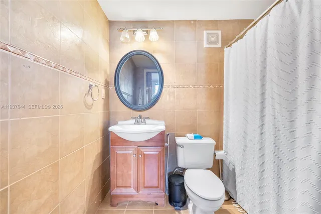 a bathroom with a toilet a sink and a shower curtain
