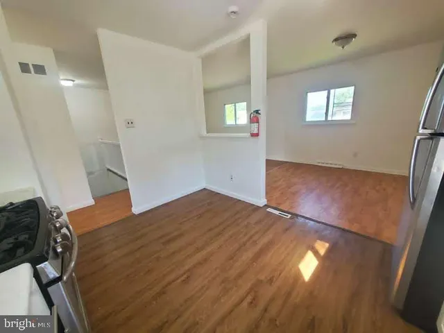 a view of empty room with window and wooden floor