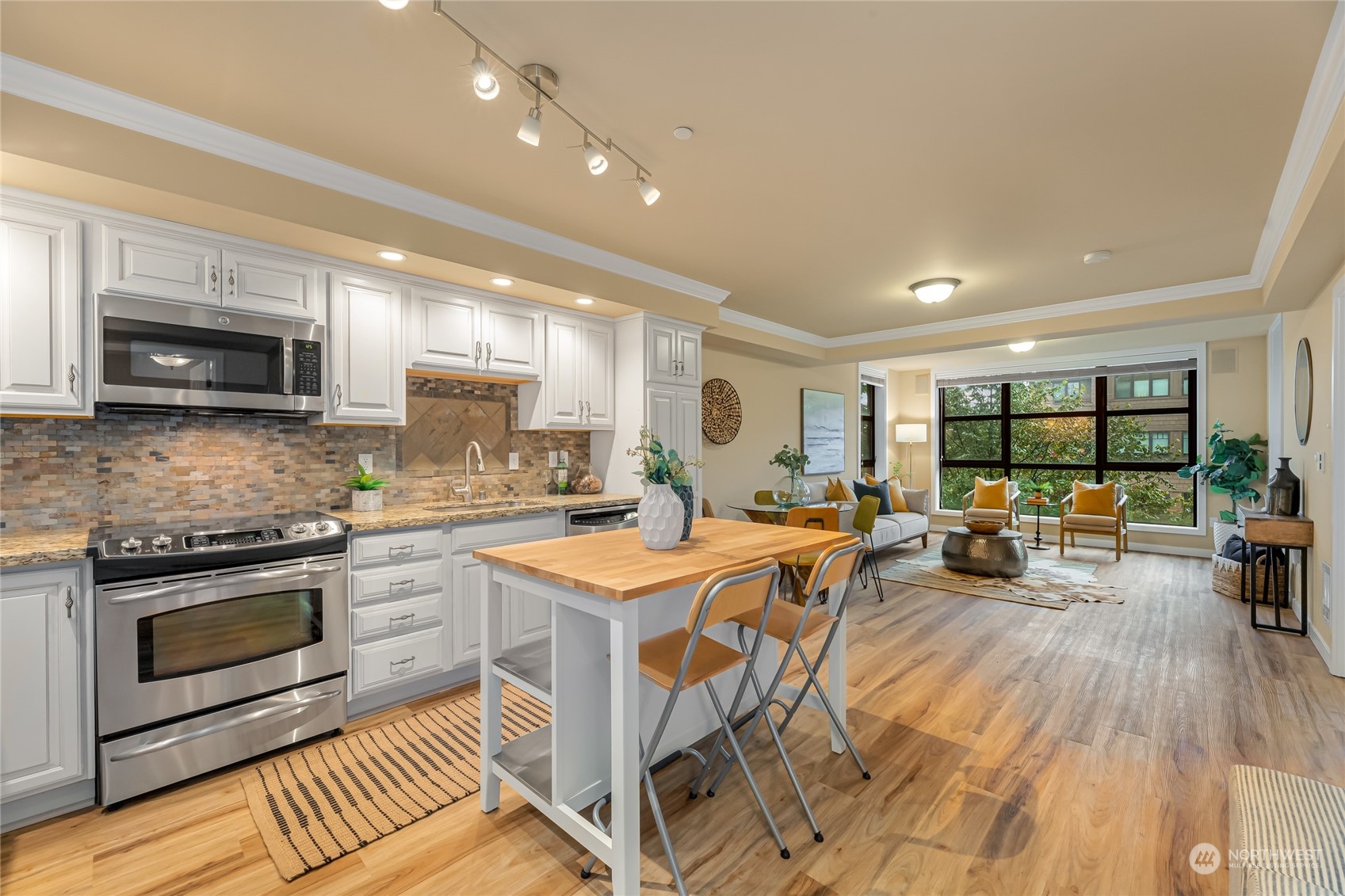4116 California Avenue Southwest, Unit 313 Seattle, WA 98116 - Photo 3 of 18 a kitchen with stainless steel appliances granite countertop a stove top oven a sink dishwasher a dining table and chairs with wooden floor