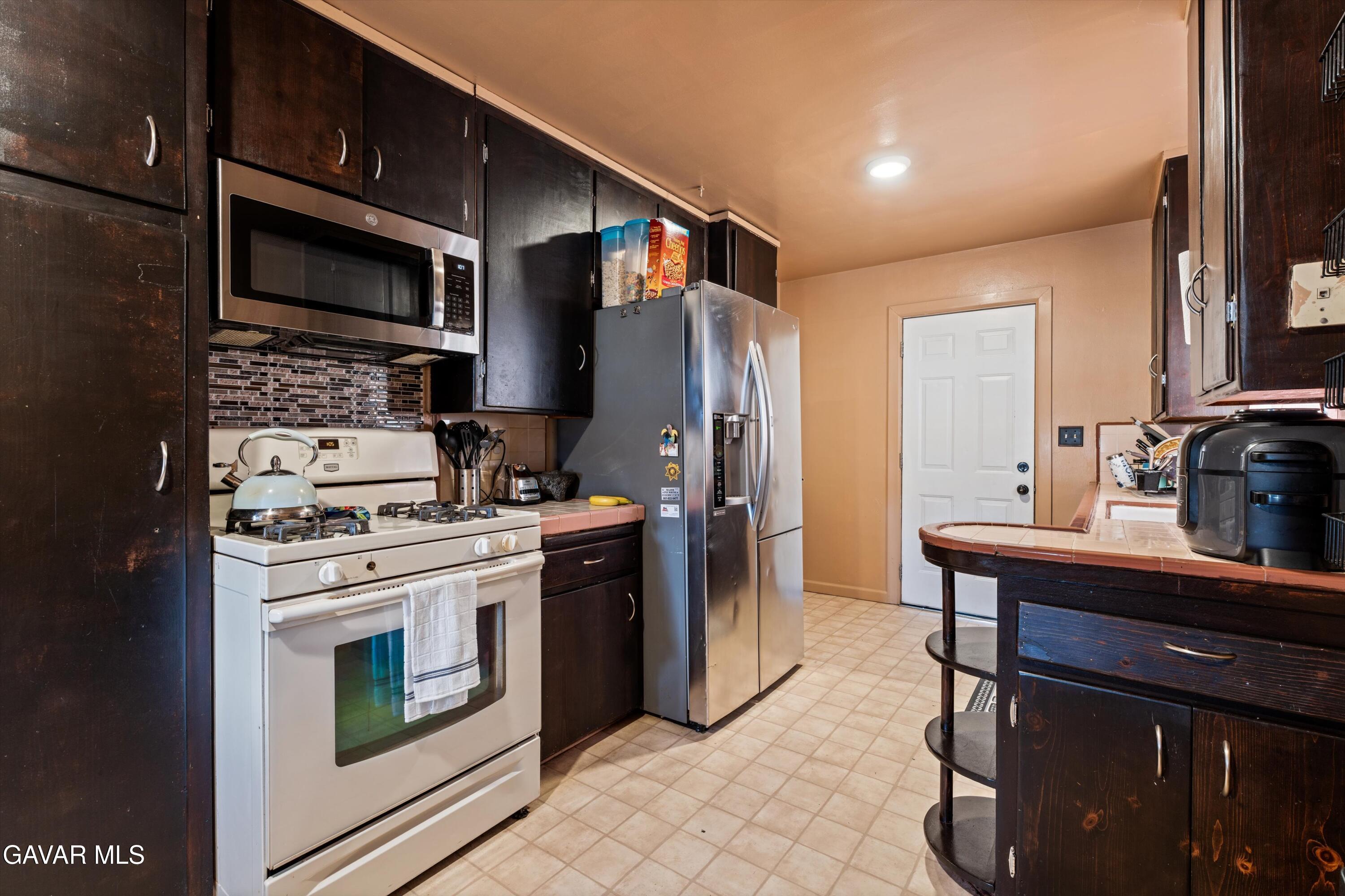 817 Oakwood Street Tehachapi, CA 93561 - Photo 4 of 12 a kitchen with stainless steel appliances granite countertop a stove a refrigerator and a microwave
