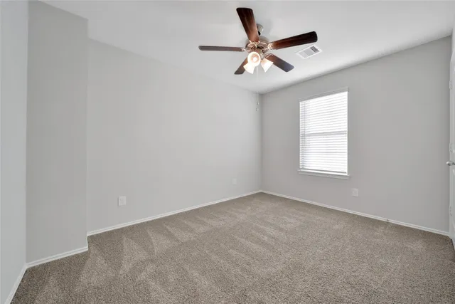 an empty room with a window and a fan