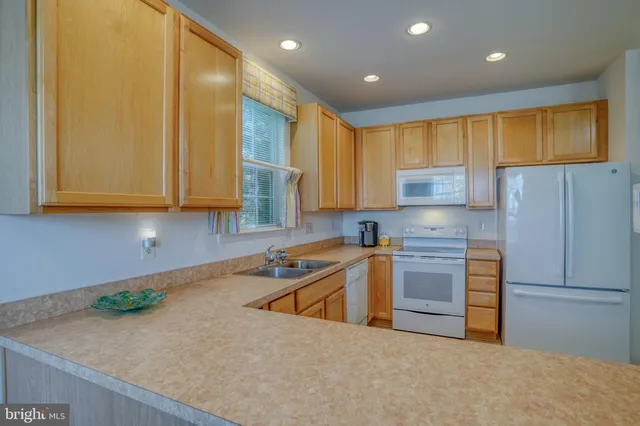 a kitchen with stainless steel appliances granite countertop wooden cabinets a stove a sink and a white refrigerator