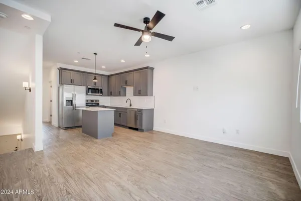 a kitchen with a refrigerator a stove top oven a sink dishwasher and a dining table with wooden floor