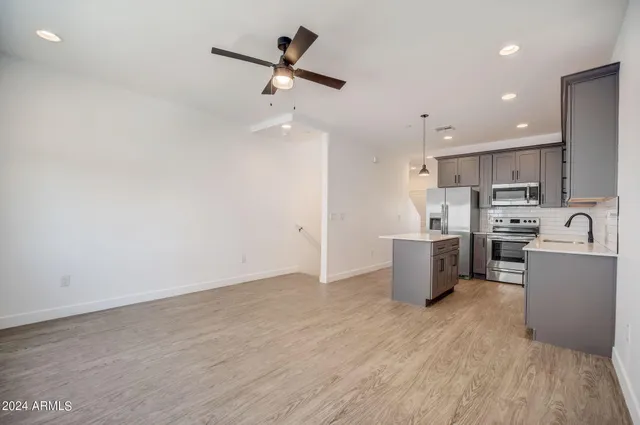 a kitchen with stainless steel appliances a sink a stove a refrigerator cabinets and wooden floor