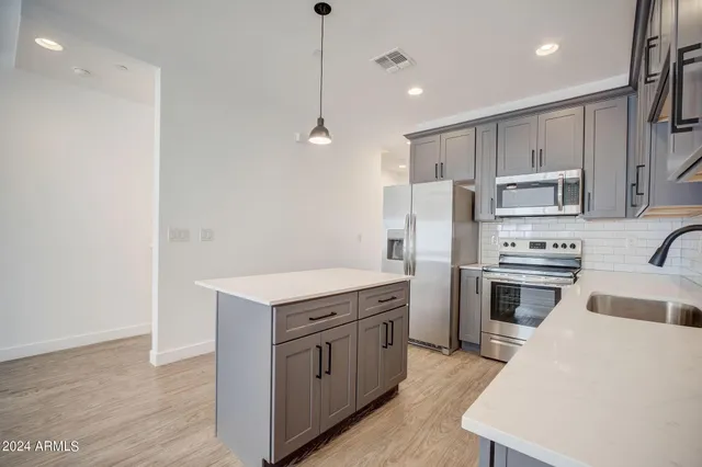 a kitchen with a sink a counter space appliances and cabinets
