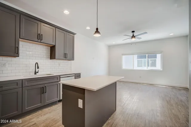 a kitchen with stainless steel appliances granite countertop a sink a stove a refrigerator and island with wooden floor