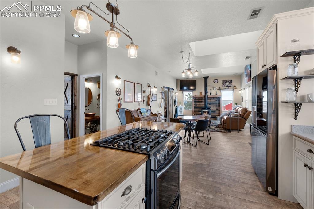 311 Knickerbocker Road Silver Cliff, CO 81252 - Photo 12 of 50 a kitchen with stainless steel appliances granite countertop a stove top oven a refrigerator a dining table and chairs with wooden floor