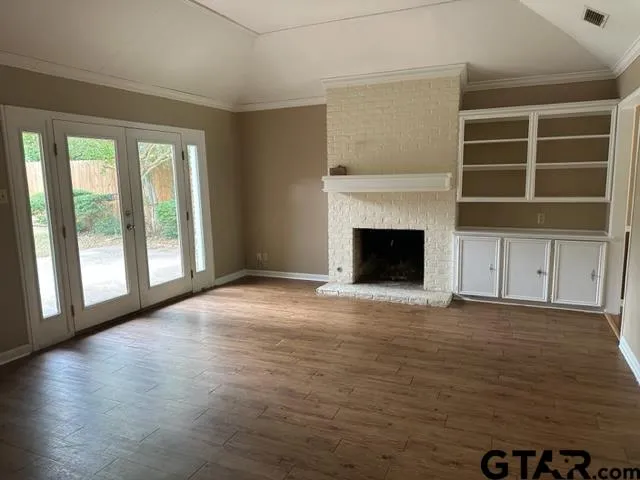 an empty room with windows and fireplace