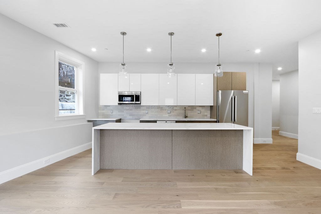 21 Glen Road, Unit 10 Boston, MA 02130 - Photo 2 of 11 a large kitchen with stainless steel appliances kitchen island a large counter top a sink and a chandelier