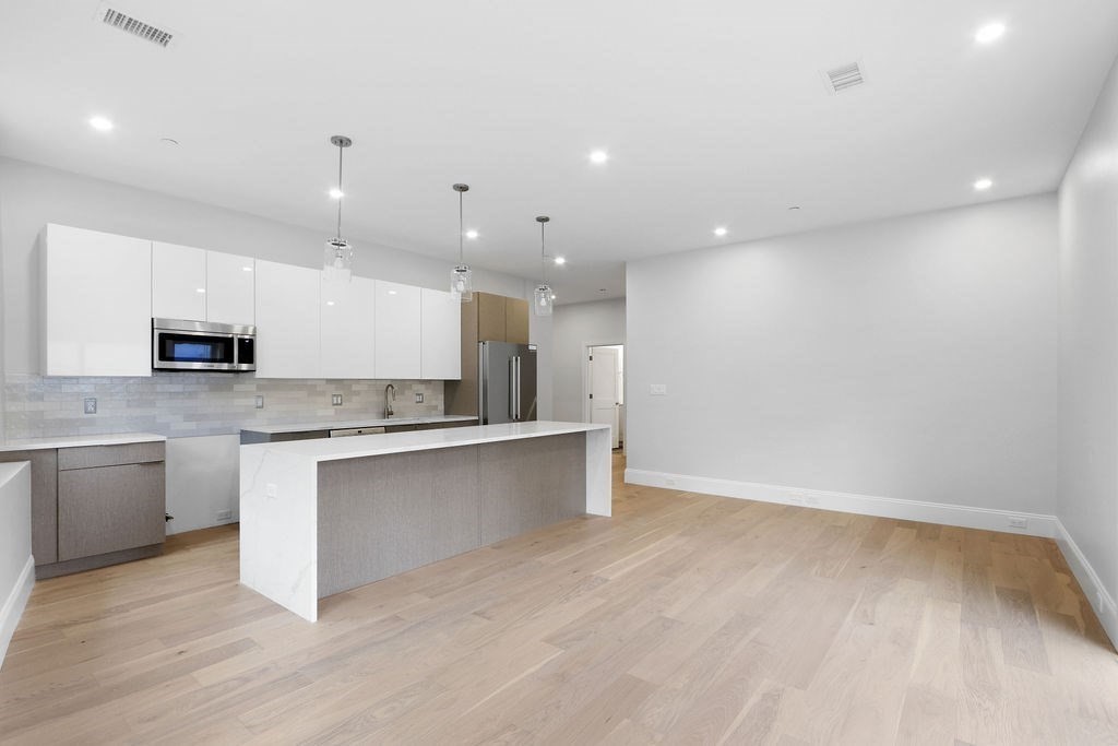 21 Glen Road, Unit 10 Boston, MA 02130 - Photo 3 of 11 a large kitchen with a large counter top a sink stainless steel appliances and cabinets