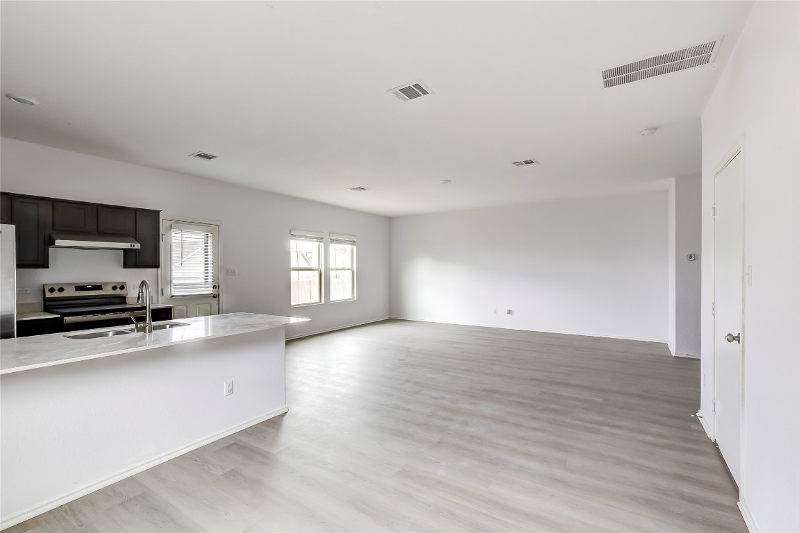 772 Circle Way Jarrell, TX 76537 - Photo 35 of 35 Kitchen featuring stainless steel electric range oven, light stone counters, light wood-style flooring, open floor plan, and under cabinet range hood