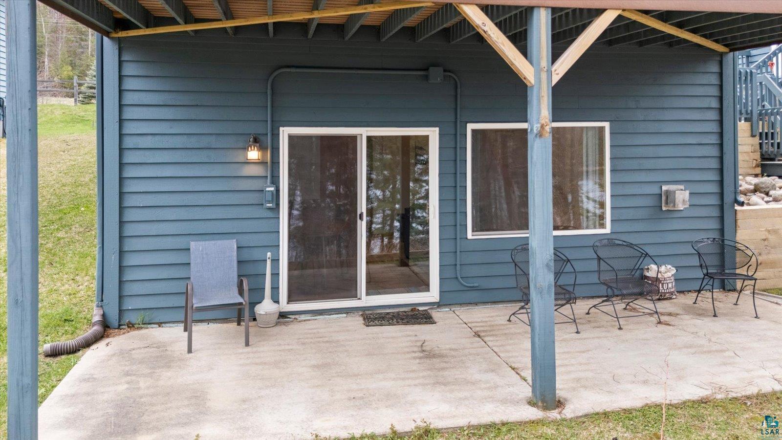 6266 Giants Ridge Road Biwabik, MN 55705 - Photo 3 of 37 Lower-level concrete patio featuring a sliding glass door entry, single window, exterior wall lighting, and horizontal siding
