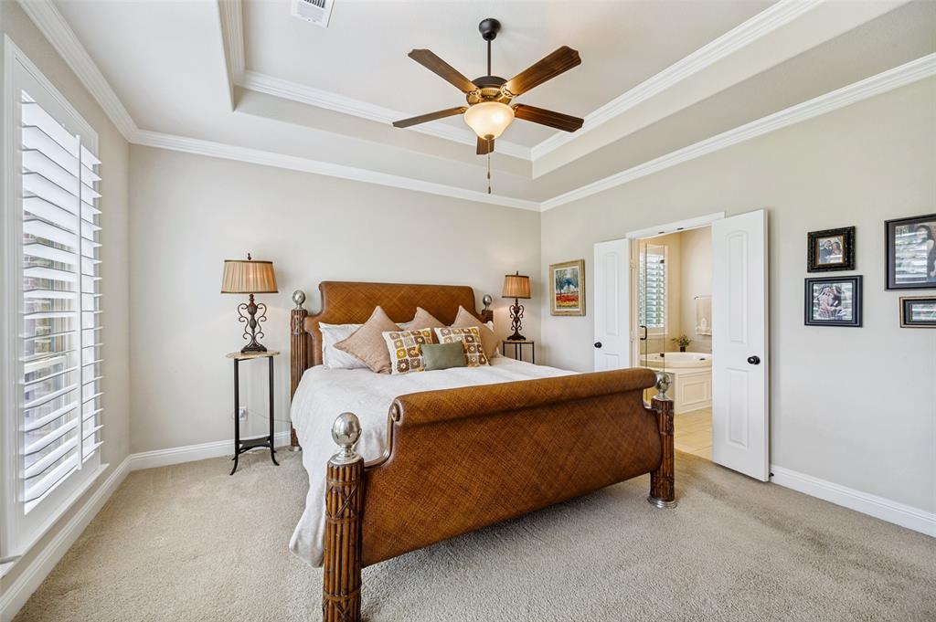 3036 Avondale The Colony, TX 75056 - Photo 19 of 40 A spacious and relaxing primary suite featuring tray ceilings, plantation shutters, soft natural light, and a private ensuite bath.