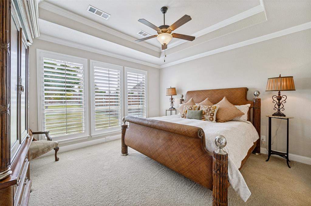 3036 Avondale The Colony, TX 75056 - Photo 20 of 40 A light-filled primary suite featuring tray ceilings, plantation shutters, and large windows with a beautiful view of the expansive backyard.