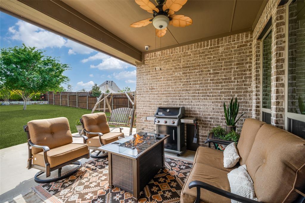 3036 Avondale The Colony, TX 75056 - Photo 29 of 40 Enjoy outdoor living year-round on this covered patio featuring a cozy fire table, ceiling fan, and views of the spacious backyard.