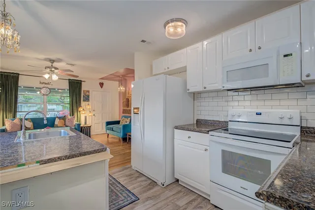 a kitchen with granite countertop a stove a sink and a refrigerator