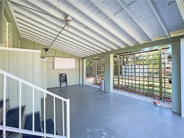 a view of a porch with wooden floor and roof with a garden view