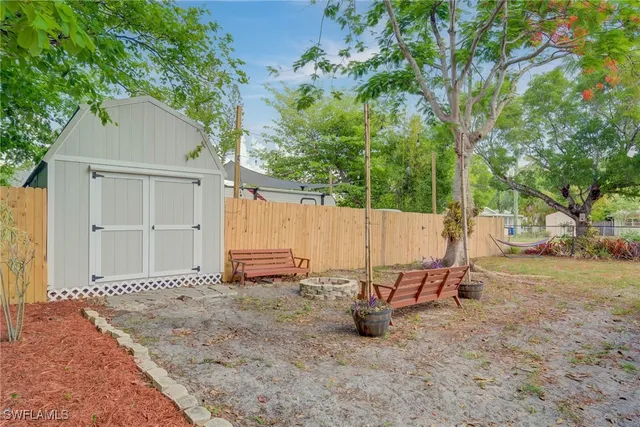 a view of a backyard with wooden fence and a bench