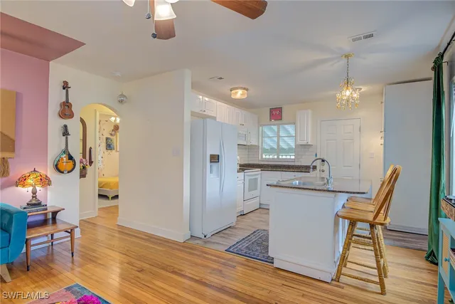 a kitchen with stainless steel appliances granite countertop a dining table chairs and chandelier