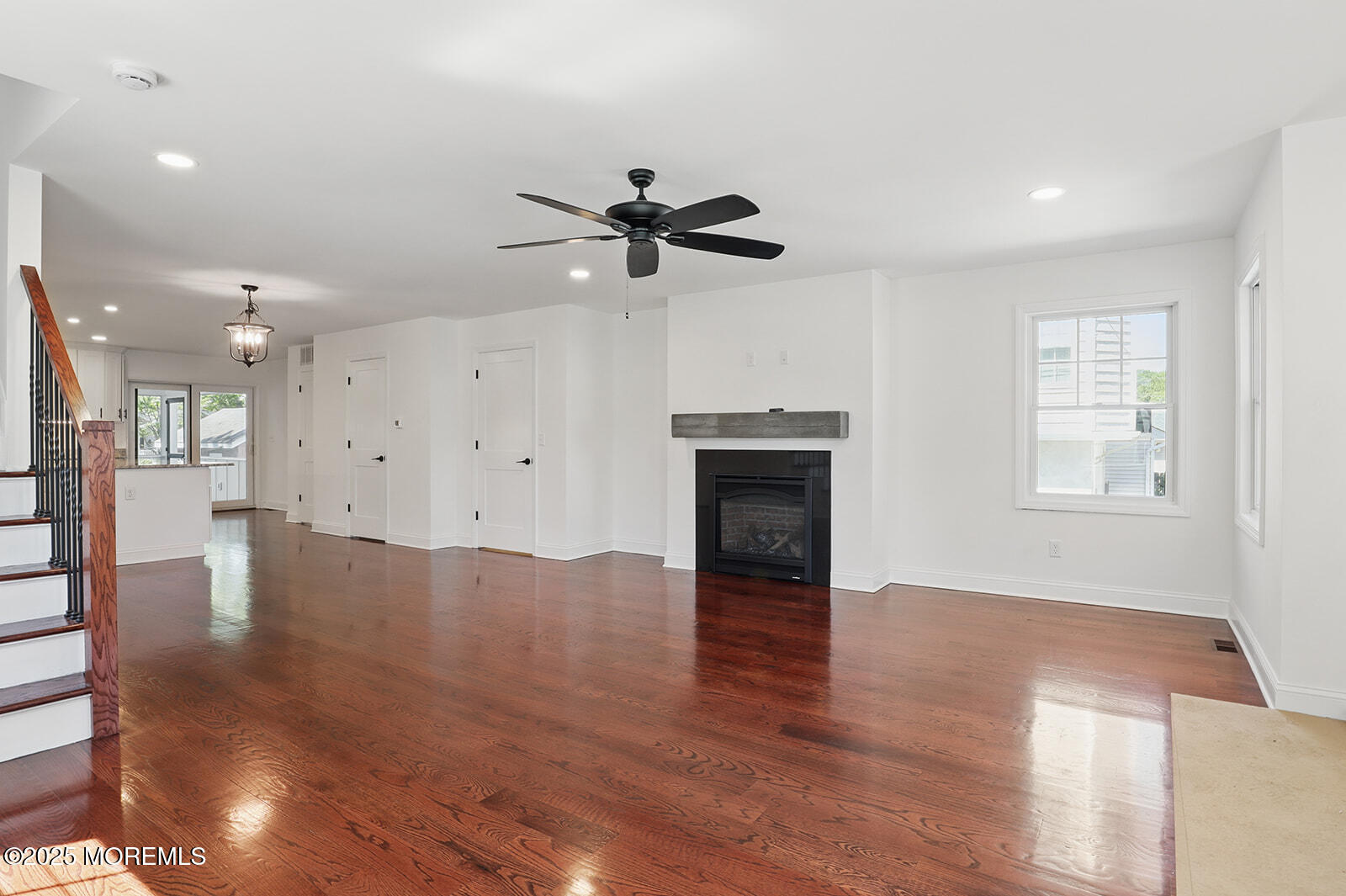 18 Neptune Place North Middletown, NJ 07748 - Photo 7 of 49 an empty room with wooden floor a ceiling fan and kitchen view
