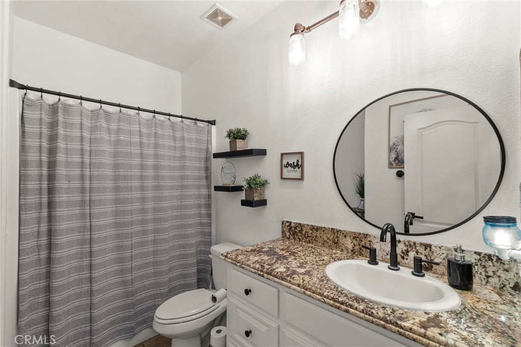 7381 Cygnet Road Phelan, CA 92371 - Photo 26 of 64 a bathroom with a granite countertop sink mirror and toilet