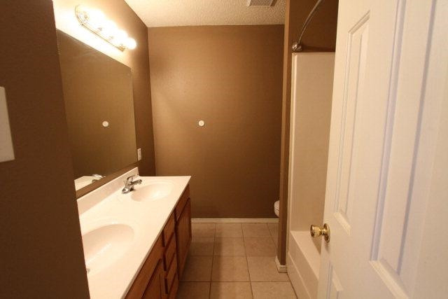 2723 110th Street Lubbock, TX 79423 - Photo 9 of 10 a bathroom with a tub sink and mirror